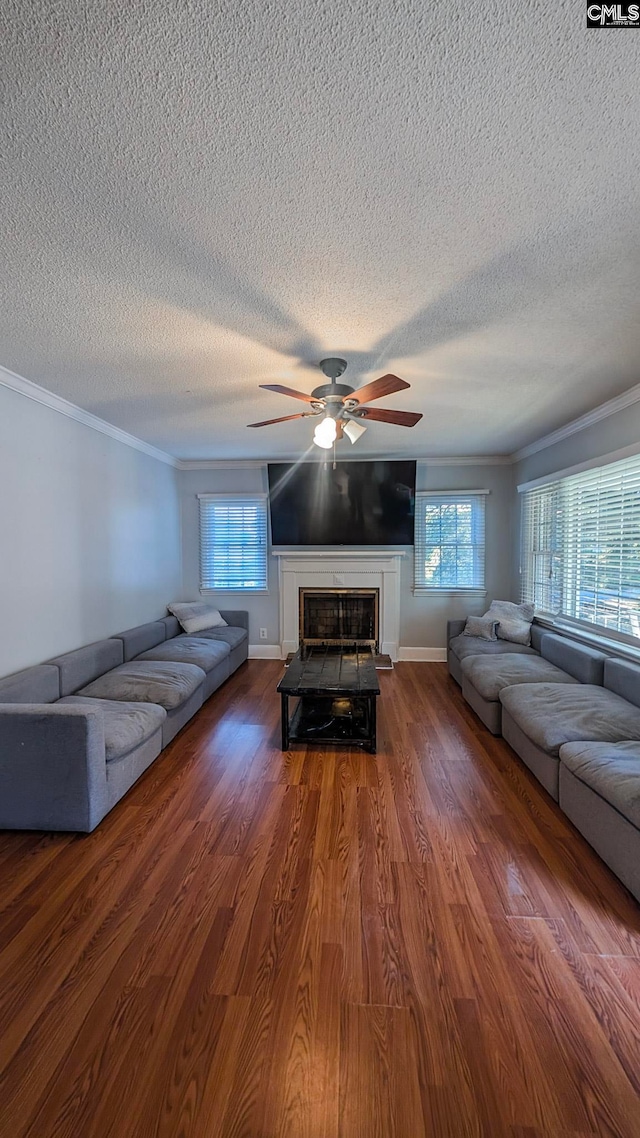 unfurnished living room with a fireplace with raised hearth, ceiling fan, wood finished floors, and crown molding