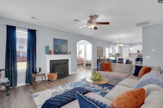 living room featuring arched walkways, a fireplace, visible vents, and plenty of natural light