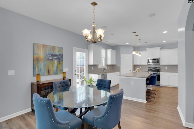 dining room with light wood finished floors, baseboards, a chandelier, and recessed lighting