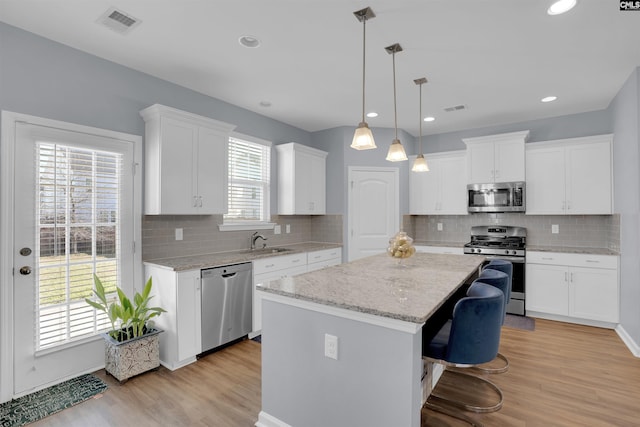 kitchen with appliances with stainless steel finishes, a sink, white cabinetry, and a center island