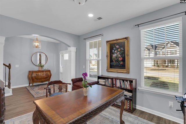 office space featuring arched walkways, wood finished floors, decorative columns, and baseboards