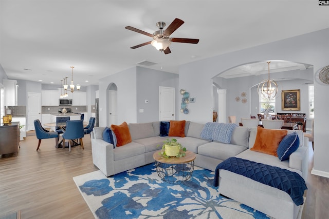 living area featuring visible vents, arched walkways, ceiling fan with notable chandelier, light wood-type flooring, and recessed lighting