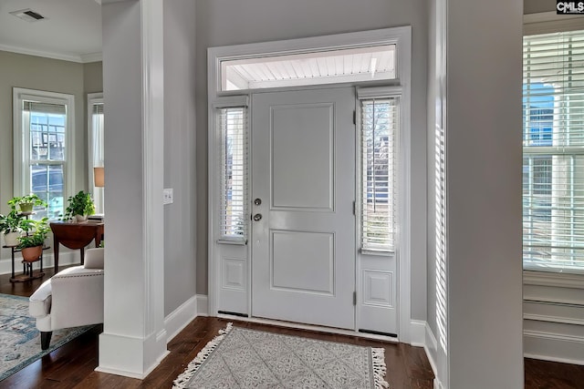 entrance foyer featuring dark wood-type flooring, a healthy amount of sunlight, ornamental molding, and visible vents