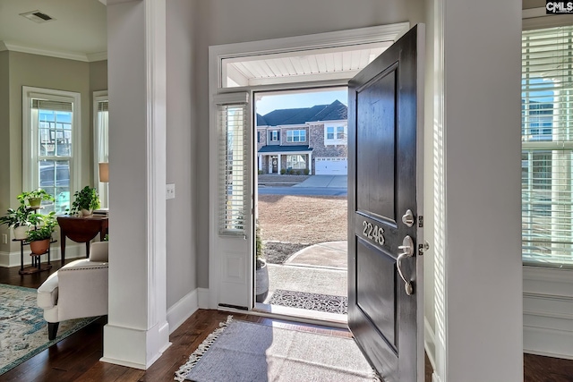 foyer featuring baseboards, visible vents, dark wood finished floors, and ornamental molding