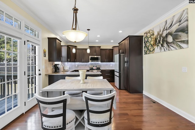 kitchen featuring decorative backsplash, ornamental molding, stainless steel appliances, and dark brown cabinets