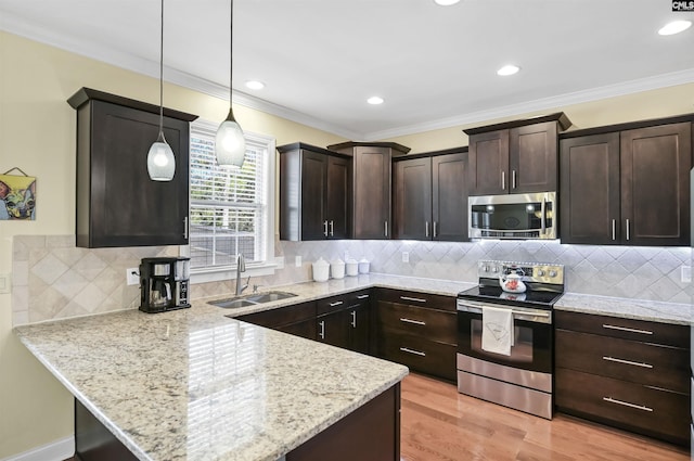 kitchen with dark brown cabinetry, appliances with stainless steel finishes, a peninsula, crown molding, and a sink