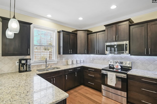 kitchen featuring light wood-style floors, ornamental molding, stainless steel appliances, and a sink