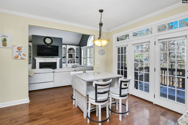 dining space featuring ornamental molding, a fireplace, dark wood finished floors, and baseboards