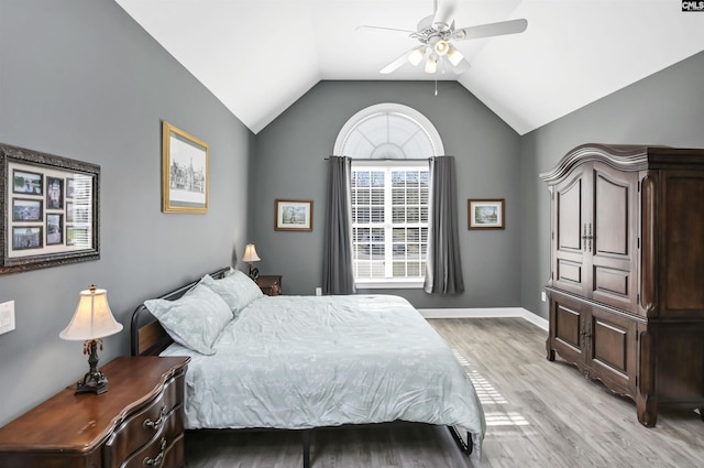 bedroom with a ceiling fan, vaulted ceiling, light wood-style flooring, and baseboards