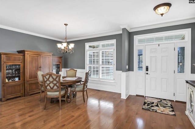 dining space featuring a chandelier, wainscoting, wood-type flooring, and crown molding