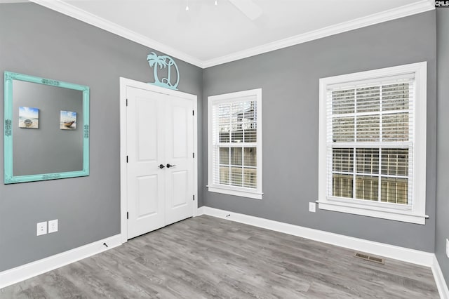 foyer with baseboards, visible vents, crown molding, and wood finished floors