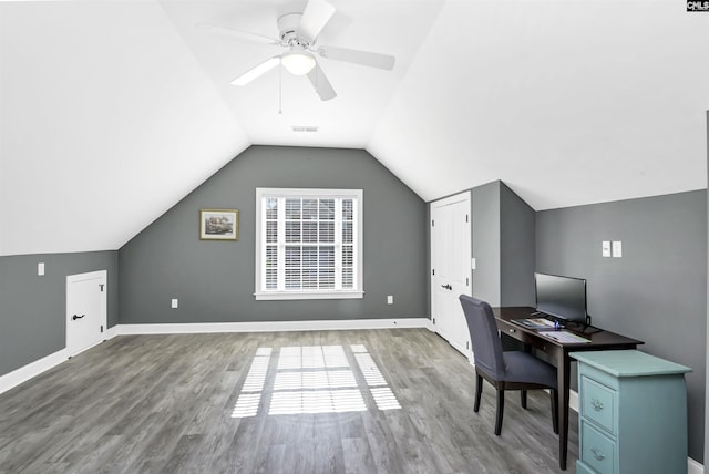 unfurnished office featuring lofted ceiling, wood finished floors, visible vents, and baseboards