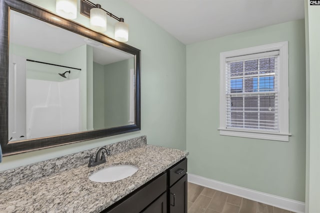 bathroom with walk in shower, vanity, baseboards, and wood finished floors