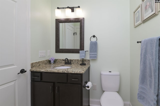 half bath featuring vanity, toilet, and baseboards