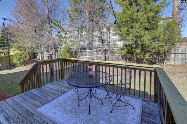 wooden terrace with outdoor dining space and a fenced backyard