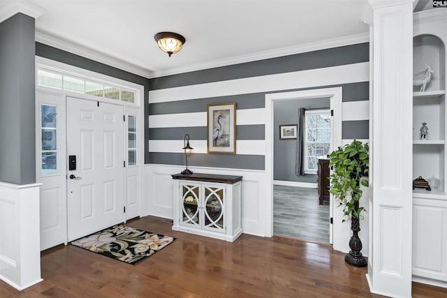 foyer featuring dark wood-style flooring, crown molding, and decorative columns