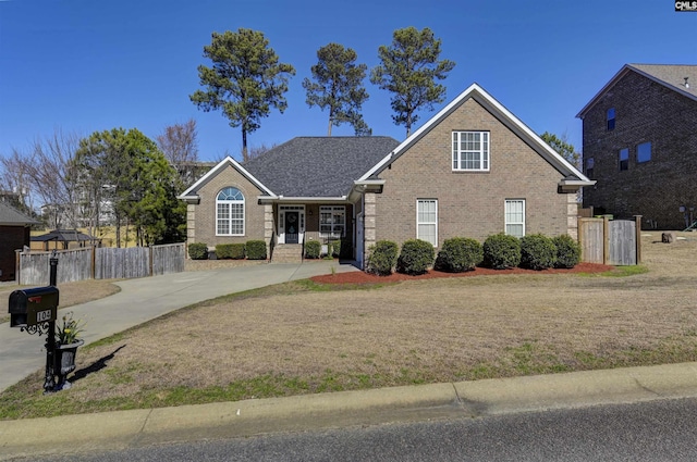 traditional-style home with brick siding, fence, and a front lawn