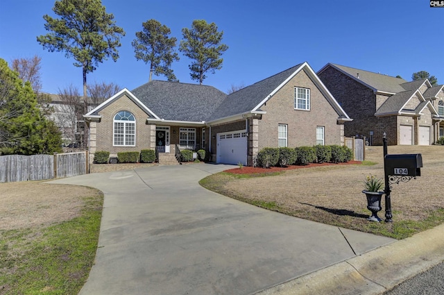 view of front of house featuring driveway, brick siding, an attached garage, and fence