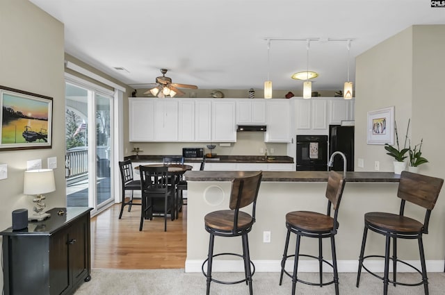 547 Harbor Heights Dr, Lexington, SC 29072 - kitchen featuring dark countertops, white cabinetry, a peninsula, under cabinet range hood, and black appliances