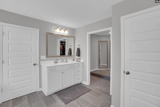 full bathroom with baseboards, a walk in closet, and vanity