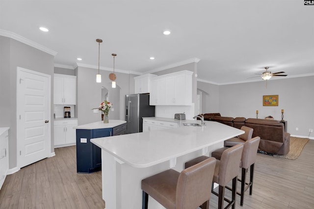 kitchen featuring a sink, blue cabinetry, stainless steel fridge, and light wood-style floors