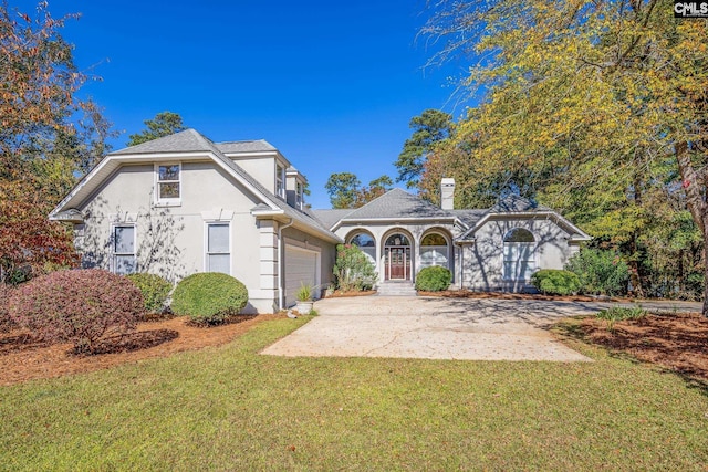 view of front of property with driveway, a front lawn, an attached garage, and stucco siding