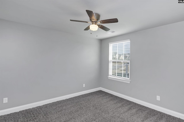 spare room featuring ceiling fan, visible vents, baseboards, and dark carpet