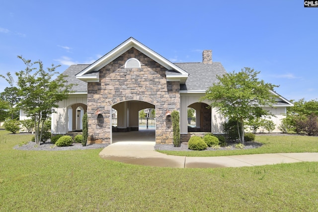 view of front facade featuring stone siding, a front lawn, a chimney, and a shingled roof