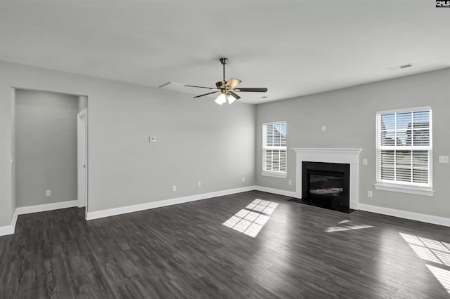 unfurnished living room featuring a fireplace with flush hearth, a ceiling fan, visible vents, baseboards, and dark wood finished floors