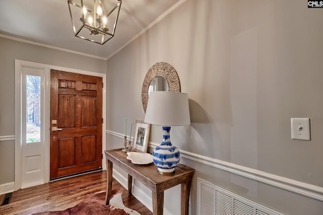 entrance foyer with dark wood-type flooring, a notable chandelier, crown molding, and visible vents