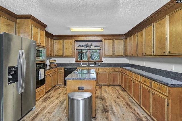 kitchen featuring brown cabinets, a sink, light wood-style flooring, and black appliances