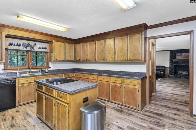 kitchen featuring light wood finished floors, brown cabinetry, a sink, a textured ceiling, and black appliances