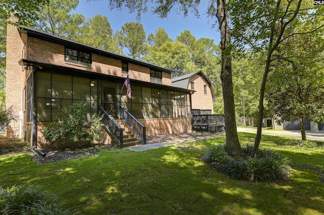 rear view of house with a sunroom, stairway, brick siding, and a yard