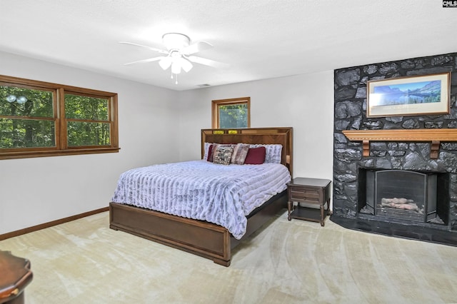 bedroom featuring a large fireplace, baseboards, a ceiling fan, a textured ceiling, and carpet floors