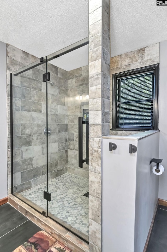 bathroom with a stall shower, a textured ceiling, and baseboards