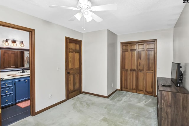 unfurnished bedroom featuring connected bathroom, light colored carpet, a sink, baseboards, and a closet