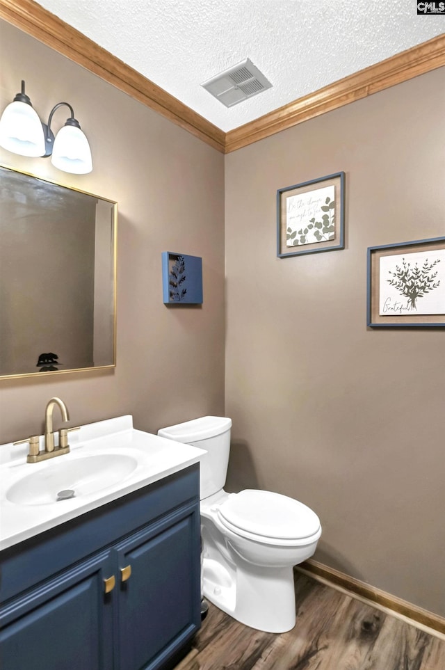 half bath with a textured ceiling, visible vents, crown molding, and wood finished floors