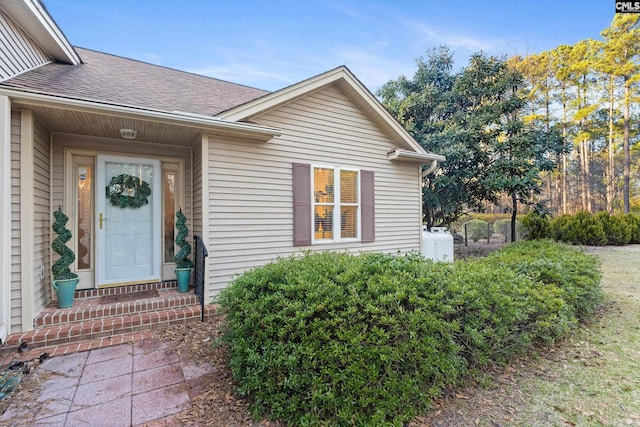 view of exterior entry with a shingled roof