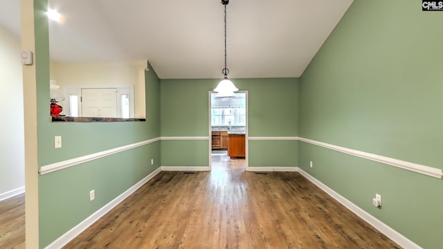 unfurnished dining area with hardwood / wood-style flooring and baseboards