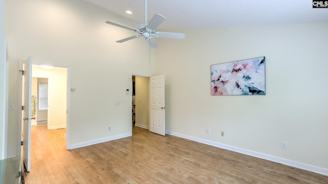 unfurnished bedroom featuring light wood-style floors, baseboards, and a high ceiling