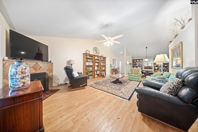 living area with a fireplace with flush hearth, lofted ceiling, a ceiling fan, and wood finished floors