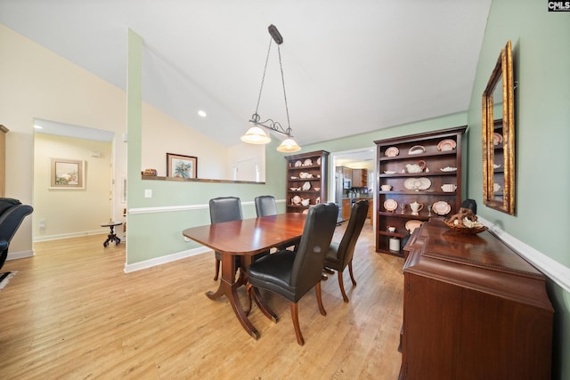 dining area featuring lofted ceiling, light wood-style flooring, and baseboards