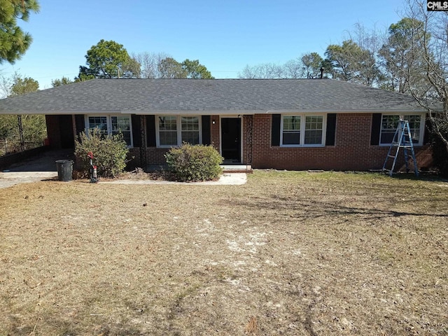 ranch-style house featuring a carport, a front yard, brick siding, and roof with shingles