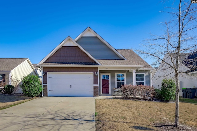 craftsman-style house featuring a garage, concrete driveway, a front lawn, and roof with shingles