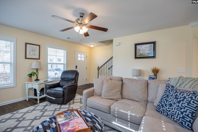 living area featuring baseboards, visible vents, a ceiling fan, wood finished floors, and stairs