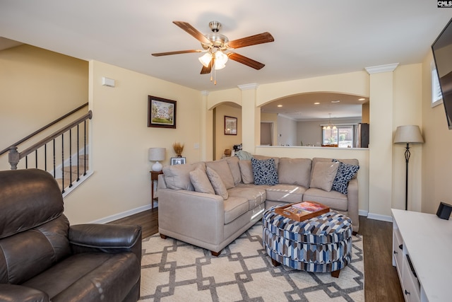 living area featuring arched walkways, stairway, a ceiling fan, wood finished floors, and baseboards