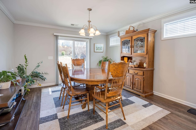 dining space with a chandelier, dark wood-type flooring, visible vents, and crown molding