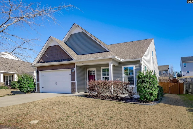 view of front facade featuring a shingled roof, concrete driveway, an attached garage, fence, and a front yard