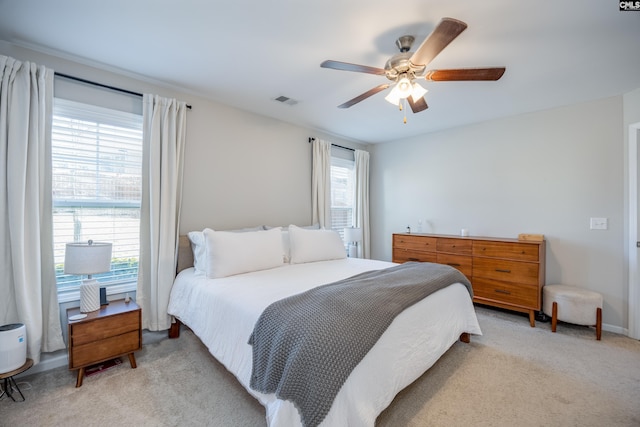 bedroom with ceiling fan, multiple windows, visible vents, and light colored carpet