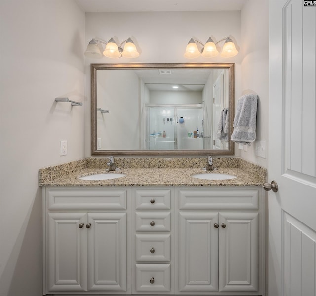 full bath featuring double vanity, a stall shower, and a sink